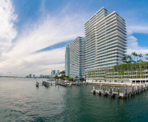 Coastline modern multi-storey building with views of Miami Beach Marina in Miami, Florida. Waterfront building with marina at the front and sky with flat clouds in the background.