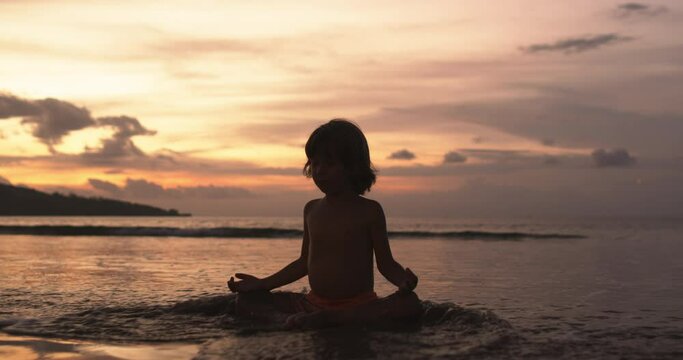 Young boy practices yoga and meditation on beach alone, solitude