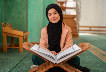 A Muslim child girl reading a holy book Quran inside the mosque. 