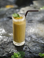 fruit juice, fruit smoothie, fruit juice, fruit juice in glass Placed on a rock near the waterfall.