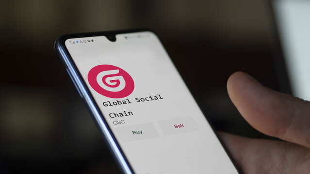 March 11 2023 London UK. An investor's analyzing the Global Social Chain  coin on screen. A phone shows the ETF's prices to invest in GSC