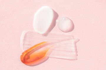 Smears of cosmetic textures of soap, mask,hyaluron on a pink background with bright light, flat lay.