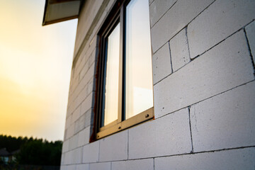 Close-up of a private house made of aerated concrete bricks with a plastic window against the backdrop of sunset