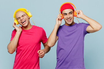 Young smiling happy fun couple two friend men wear casual clothes headphones together listen to...