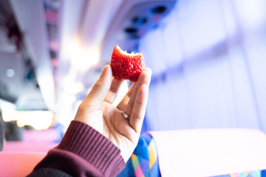 Half red strawberry fruit in hand, light blur effect background