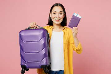 Traveler smiling woman wear casual clothes hold suitcase passport ticket isolated on plain pastel...