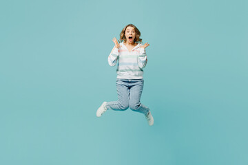 Full body young shocked excited overjoyed woman wear striped hoody jump high spread hands look camera with opened mouth isolated on plain pastel light blue cyan background studio. Lifestyle concept.