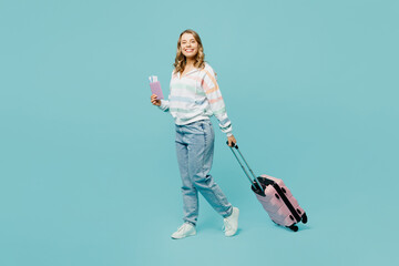Full body traveler woman wear casual clothes hold suitcase passport ticket isolated on plain blue cyan background Tourist travel abroad in free spare time rest getaway Air flight trip journey concept