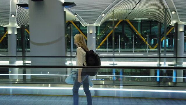 Woman on the airport terminal escalator in airport. Istanbul, Turkey. Traveler with a backpack in the airport terminal.