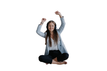 blonde Caucasian girl in headphones, blue jacket, black pants dancing against transparent background eyes closed at home sits on floor, break, time to relax. Fit Italian young entrepreneur celebrates