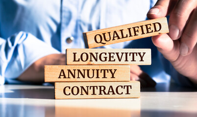 Close up on businessman holding a wooden block with "Qualified Longevity Annuity Contract" message