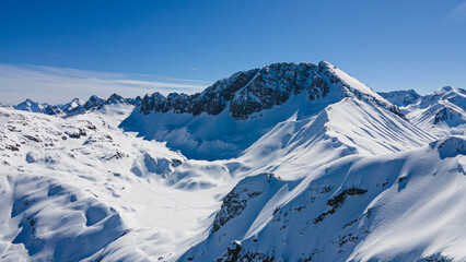 Naklejka premium Alpine ski slope mountain winter panorama with ski lift,skiers and snow covered forest.