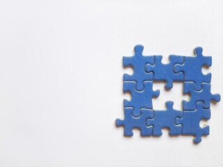 Pieces of a jigsaw puzzle that have been put together with one missing piece in the center on a white background that illustrates teamwork and problem-solving