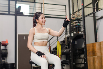 Fototapeta na wymiar Asian young muscular fit strong body sporty athletic sexy female fitness model sitting smiling taking break after workout exercising weight training in gym.