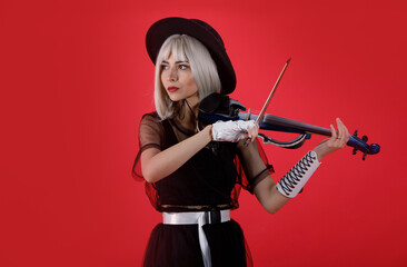 Violinist woman in the stage costume on the red background.