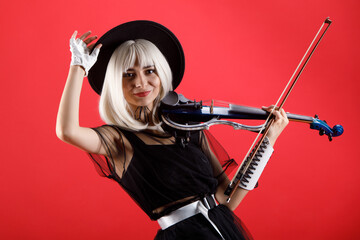 Violinist woman in the stage costume on the red background.