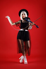 Violinist woman in the stage costume on the red background.