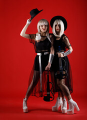 Violinist women duet in the stage costumes on the red background.
