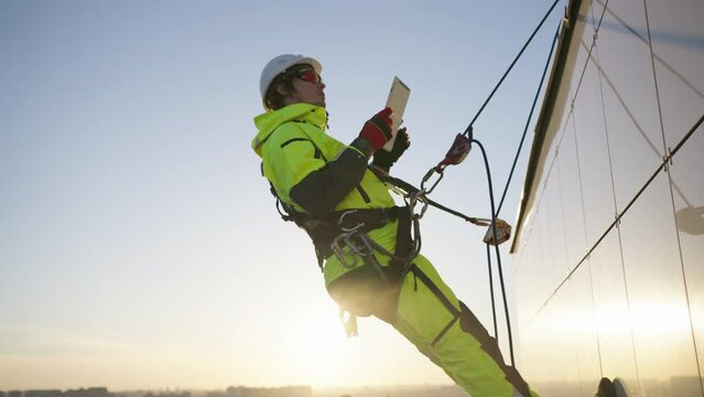 Man industrial climber with a tablet in his hands inspects the facade of a building object