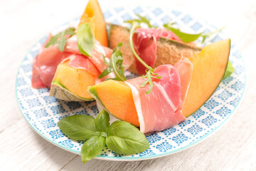 Sliced melon with ham and basil leaves