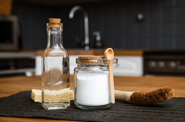 Using baking soda Sodium bicarbonate and white vinegar for home kitchen cleaning concept. White vinegar in glass bottle and baking soda in glass jar.