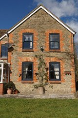 Home Exterior in United Kingdom. Old farmhouse exterior image. Located in England in the Somerset countryside. Contemporary doors and windows in traditional farm house building.