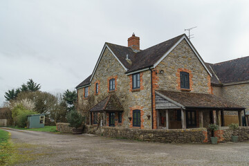 Home Exterior in United Kingdom. Old farmhouse exterior image. Located in England in the Somerset countryside. Contemporary doors and windows in traditional farm house building.