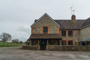 Home Exterior in United Kingdom. Old farmhouse exterior image. Located in England in the Somerset countryside. Contemporary doors and windows in traditional farm house building.