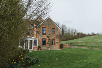 Fototapeta na wymiar Home Exterior in United Kingdom. Old farmhouse exterior image. Located in England in the Somerset countryside. Contemporary doors and windows in traditional farm house building.