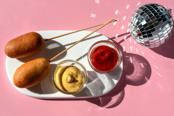 A corn dog is a sausage that is covered with a thick layer of cornmeal dough and fried in hot oil. A corn dog is an analogue of a sausage in a dough or a hot dog. Served on a wooden stick.