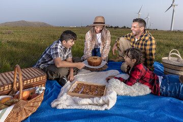 Happy family spending time together on picnic in field with turbines
