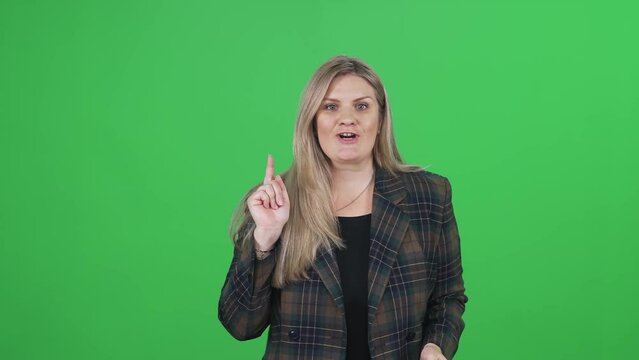 Woman in suit looks at the camera and speaks on a green background, the coach conducts the lesson online, journalist at work, chromakey.
