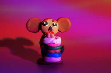 Cheburashka with a toy cake on a bright colored background. Children's toys. A cartoon character.