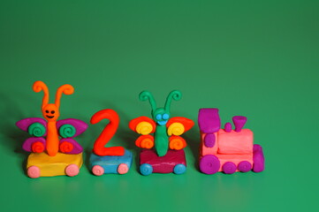 Toy train made of plasticine with butterflies and the number 2. Birthday. A festive event. Green background.