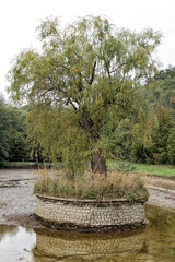 Let-out pond with central island covered by stone tiles and single tree