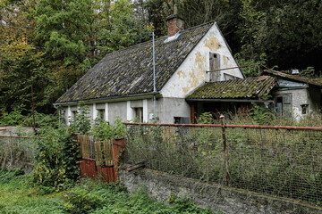 Old abandoned house with scrubby garden by the forest