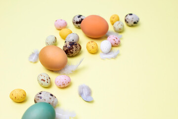 Fototapeta na wymiar Colored eggs of different sizes on a yellow background. Symbol of the Easter holiday. Easter background. Flat lay