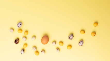 Colored eggs of different sizes on a yellow background. Symbol of the Easter holiday. Easter background. Flat lay, web banner