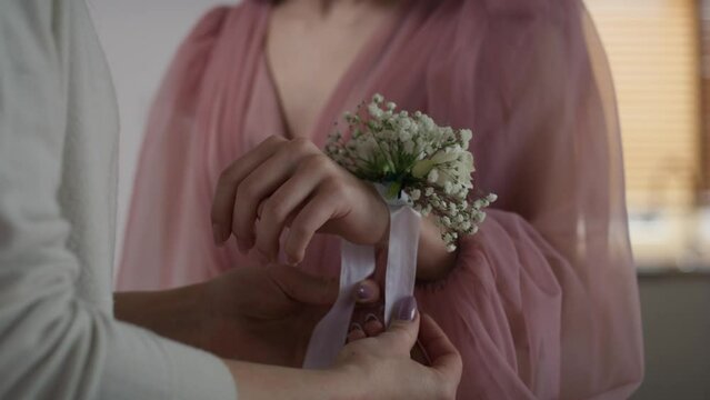 Unrecognizable  woman applying flower corsage on girl's wrist before prom. Shot with RED helium camera in 8K.     