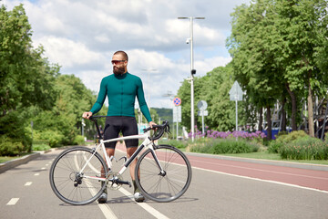 A cyclist man rides a bike in a city park along a bike path.