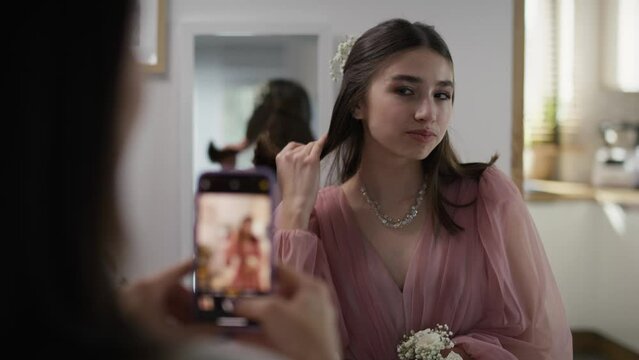 Mother taking picture of her daughter in dress before prom party. Shot with RED helium camera in 8K.