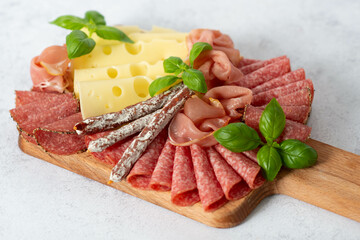 Delicacies. Cheese, prosciutto, salami on a wooden square board