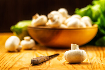 Fresh white mushrooms champignon in brown wooden bowl on wood table background