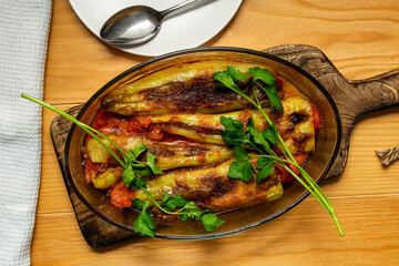 Stuffed peppers baked with tomato sauce in an oval refractory glass dish