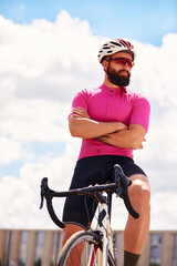 Portrait of a cyclist on the background of the sky, a man in a cycling suit with goggles cycling...