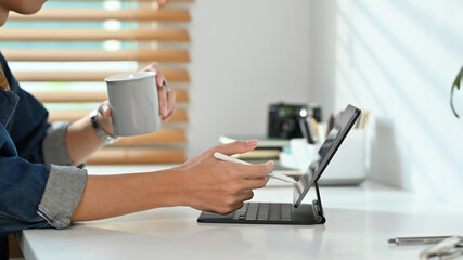 Cropped shot of young man working online on digital tablet at home. Freelance, creative occupation, e-learning concept