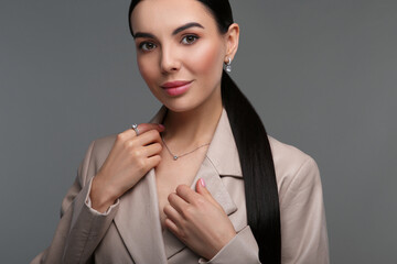 Beautiful young woman with elegant jewelry on dark grey background