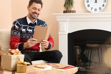 Happy man reading Christmas greeting card in living room