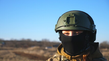 Happy military woman in helmet and balaclava fooling around around on camera. Female ukrainian army soldier showing positive emotion during war between Ukraine and russia. Faith in victory concept