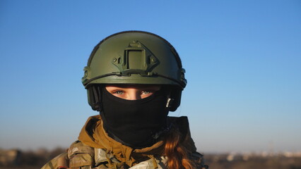 Happy military woman in helmet and balaclava fooling around around on camera. Female ukrainian army soldier showing positive emotion during war between Ukraine and russia. Faith in victory concept
